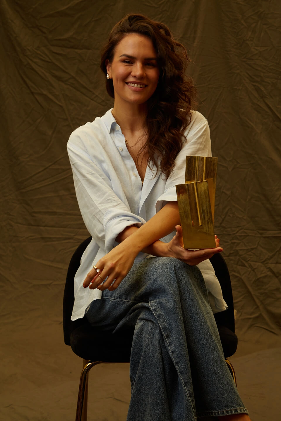 Marcela Helena sentada, segurando o vaso Vértice do Ouro