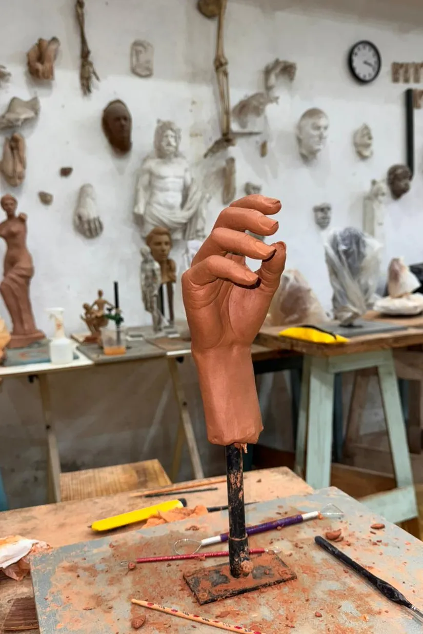 Escultura de mão em cerâmica sobre bancada do ateliê